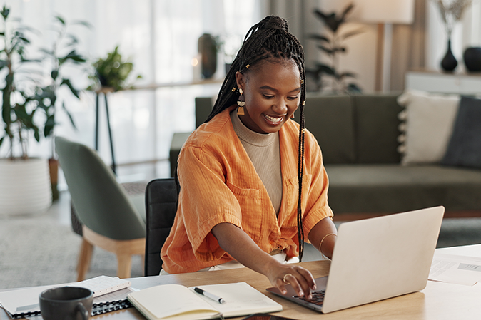 Young woman smiling at home working on her laptop
