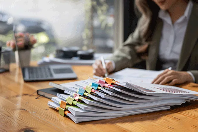 Young woman sitting at a desk with a stack of documents