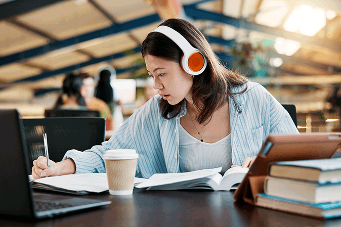 Young woman wearing headphones while studying at school