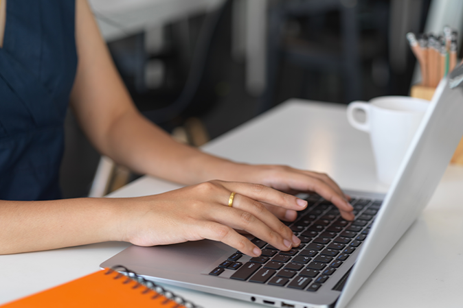 Young woman typing on a laptop sitting at a desk