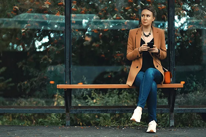 Young woman sitting alone at a bus stop 