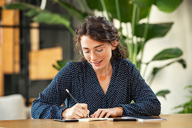 Young woman writing a letter sitting at a table