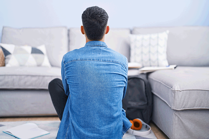 Young man sitting on the floor of living room studying