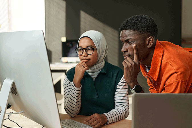 Young man and woman looking at computer with intensity