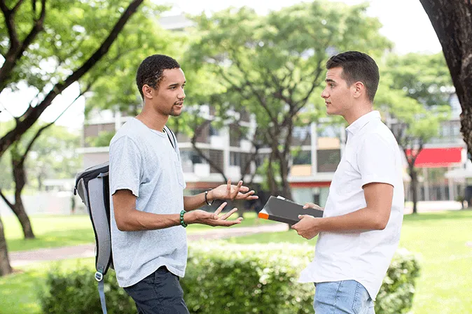 Two young men having a serious conversation outside on campus