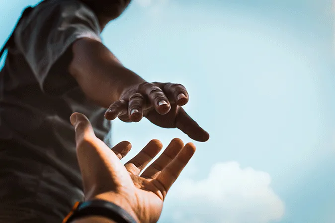 One man's hand reaching out to another man's hand