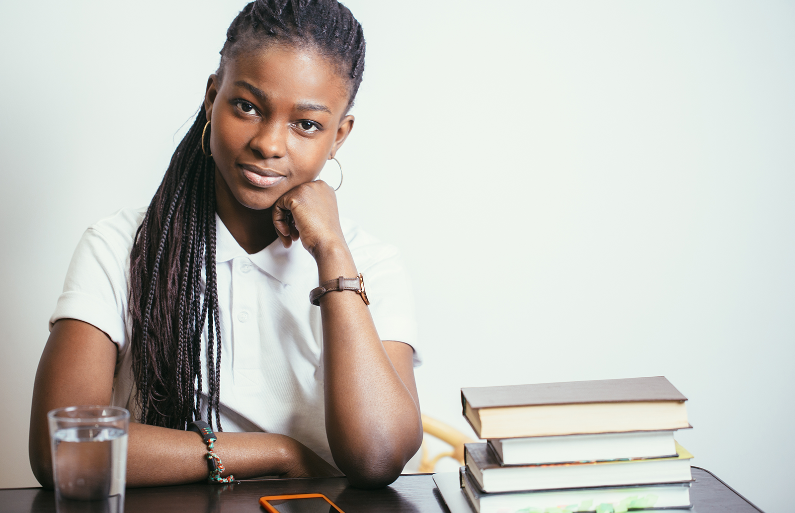 Young woman with head in hand next to a stack of books