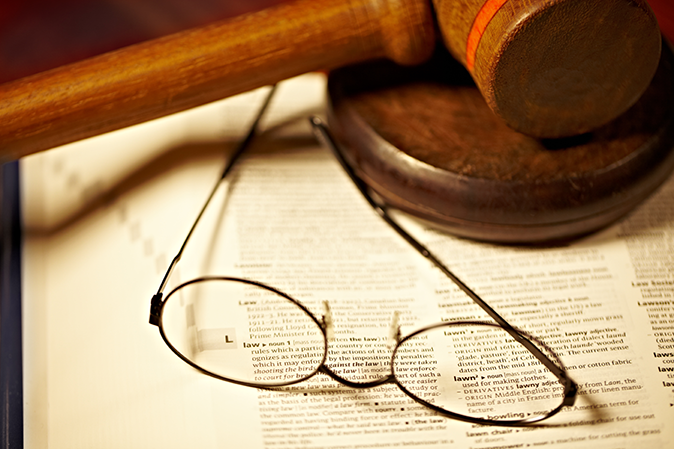 Gavel and reading glasses sitting on a dictionary