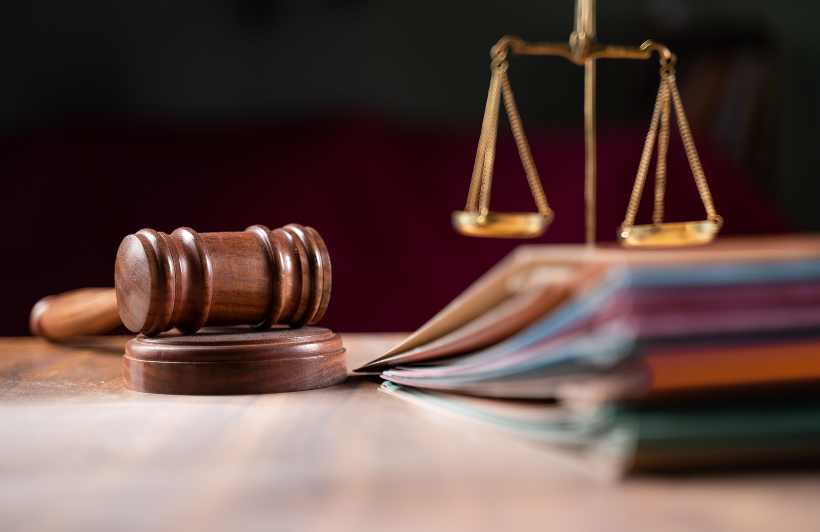 Judge's gavel sitting next to the scales of justice and a stack of files
