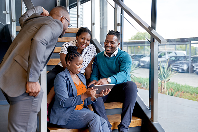 Happy group of African American businessmen and businesswomen meeting together on stairs of an office