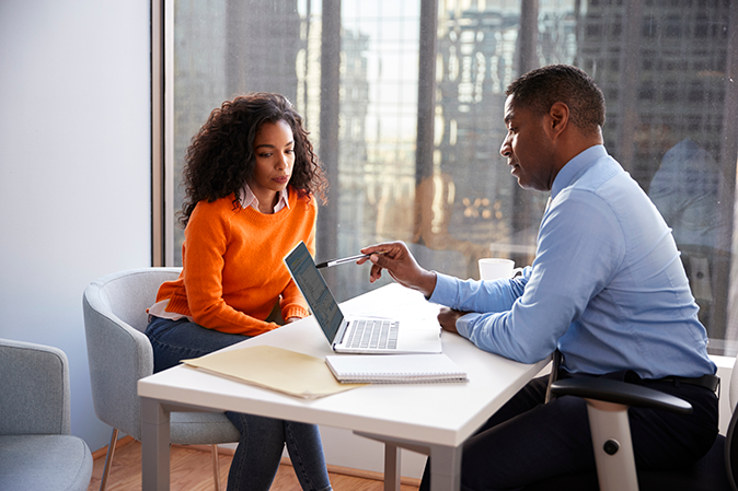 Lawyer going over document on a laptop with a client in an office