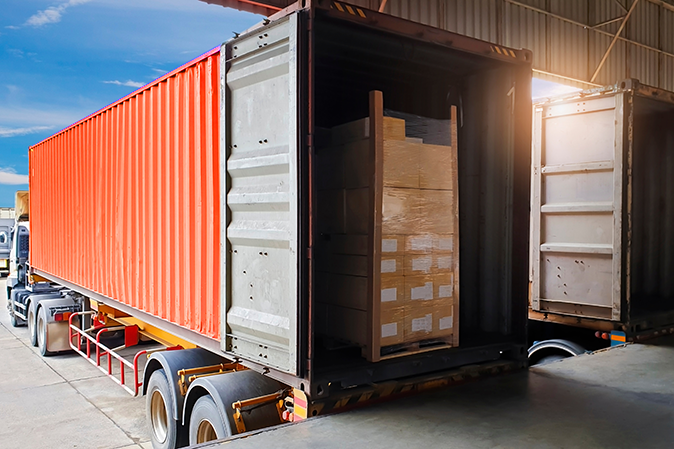 Tractor truck trailer at a loading dock with a pallet of goods inside