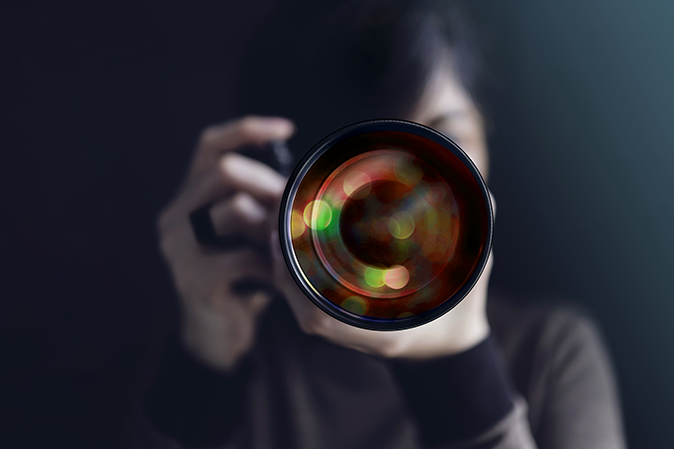 Woman holding a camera getting ready to take a picture while focusing the lens
