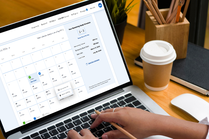 Woman sitting at a desk setting up her customizable calendar on laptop