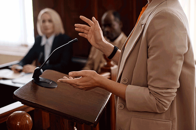 Young female lawyer at a podium speaking in a courtroom