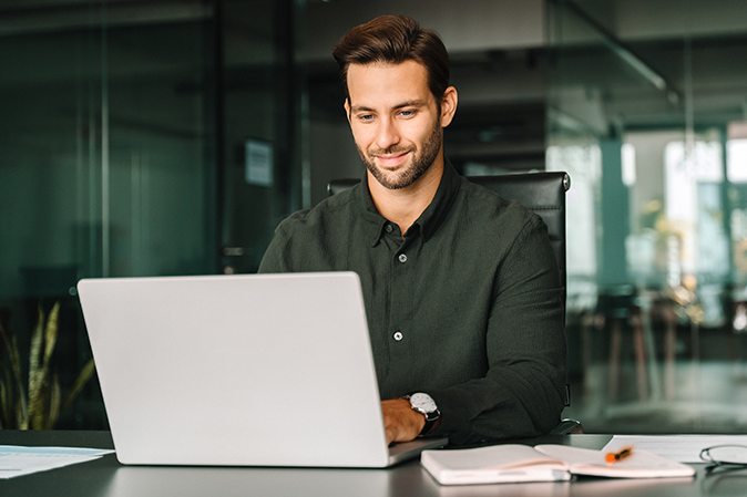 Young man sitting in front of a laptop in an office typing