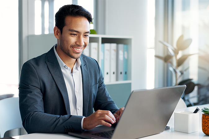 Young man in a business suit sitting in an office typing on a laptop