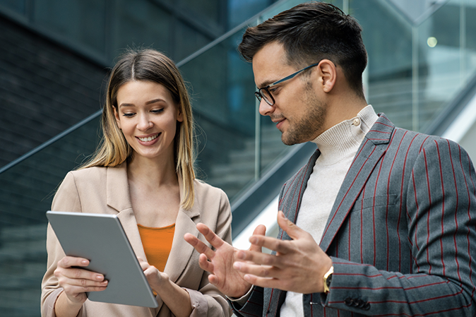 Young man and woman outside working together on a tablet