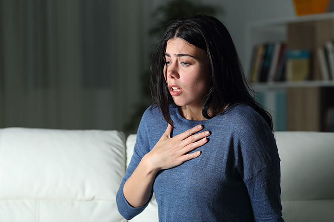 Young woman having an anxiety attack at home sitting on her couch