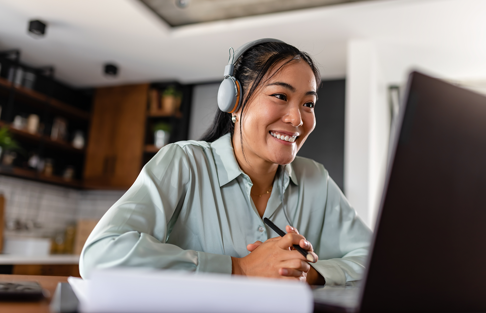Young woman wearing headphones watching a video on her laptop at her home
