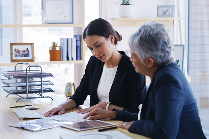 Young professional woman helping a senior woman with documents in an office