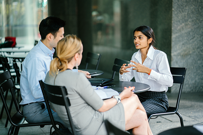 Young woman on campus sitting in front of professional man and woman for a job interview