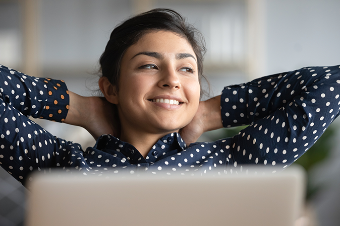Young woman leaning back relaxed in front of her laptop