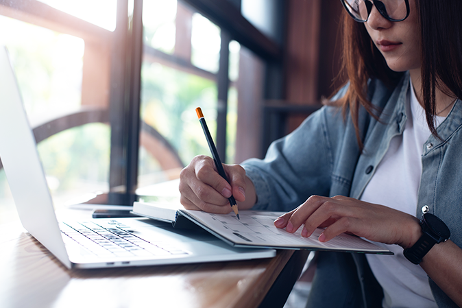 Young woman sitting at a desk in front of a laptop marking a calendar