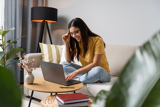Young woman at home sitting on couch in front of a laptop studying