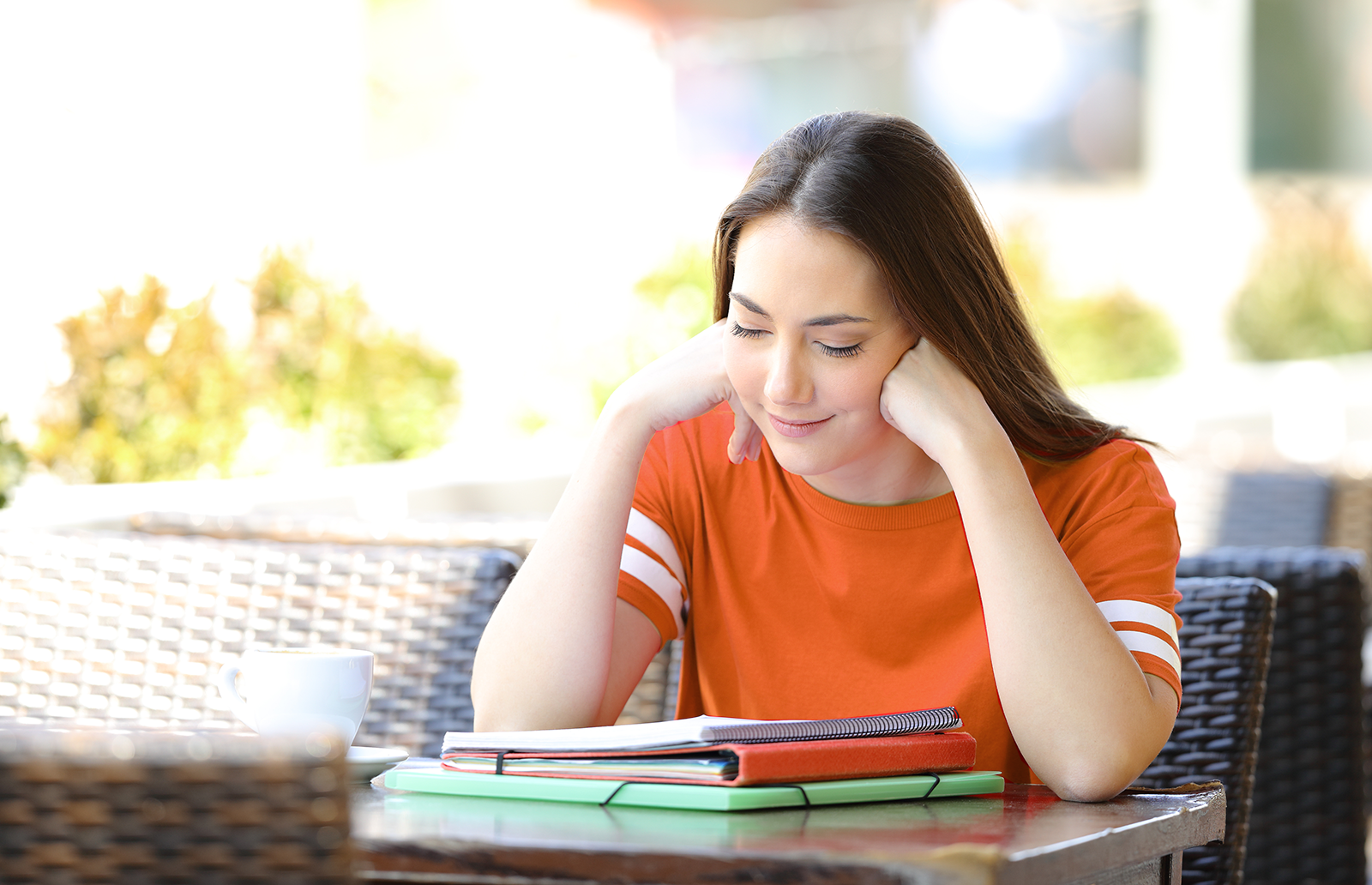 Young woman sitting outside at a table reviewing notes 