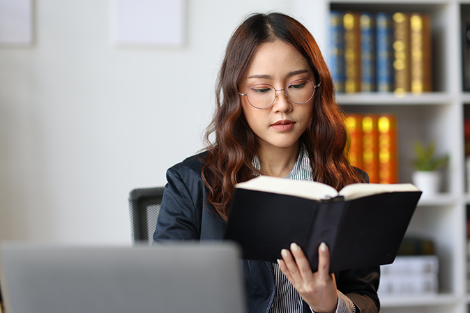 Young woman in an office reading a case book