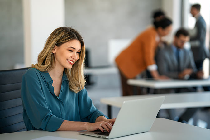 Young woman typing on laptop in a room with others