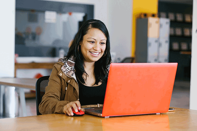 Young woman smiling while using her laptop in a classroom