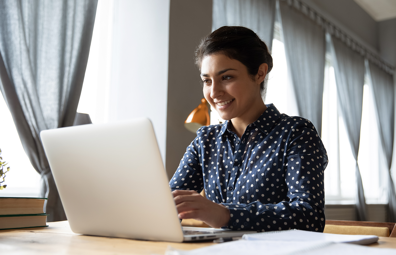 Young woman smiling while typing on a laptop 