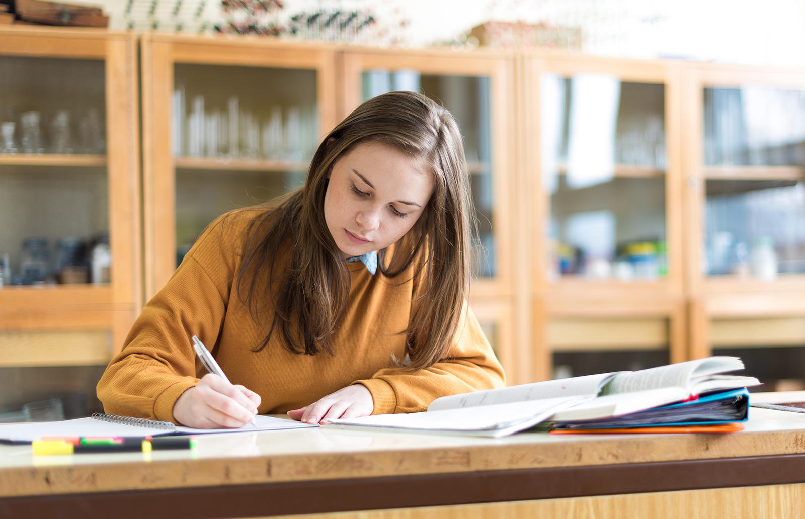 Young woman writing notes in a college classroom