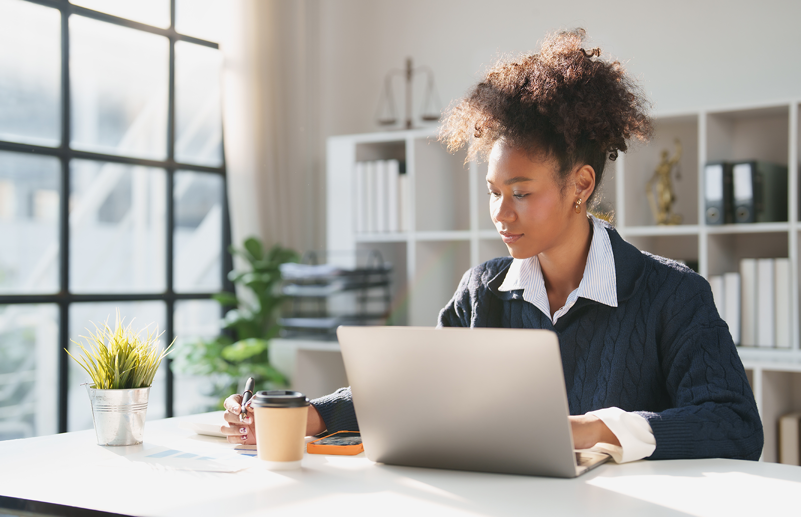 Young woman in a home office on her laptop taking notes