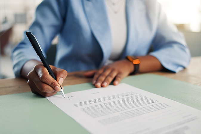 Young woman professional sitting at a desk initialing a document