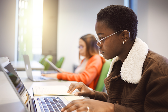 Two young women in a classroom taking an online exam