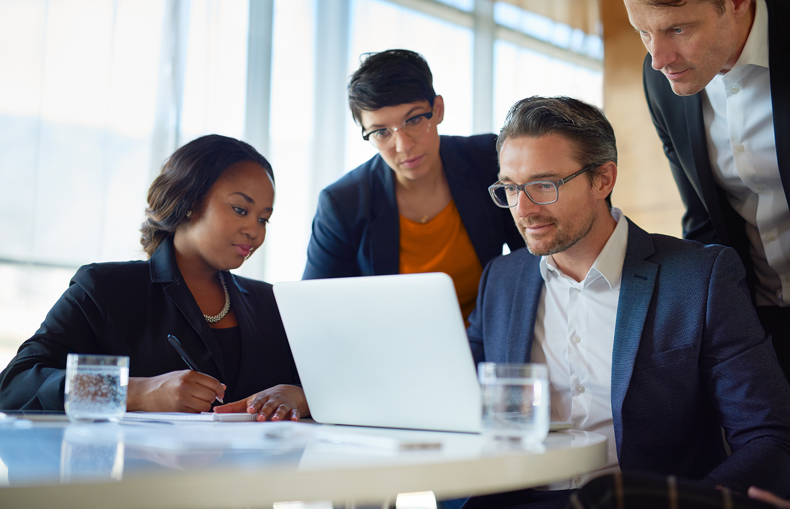 Four lawyers in front of a laptop collaborating