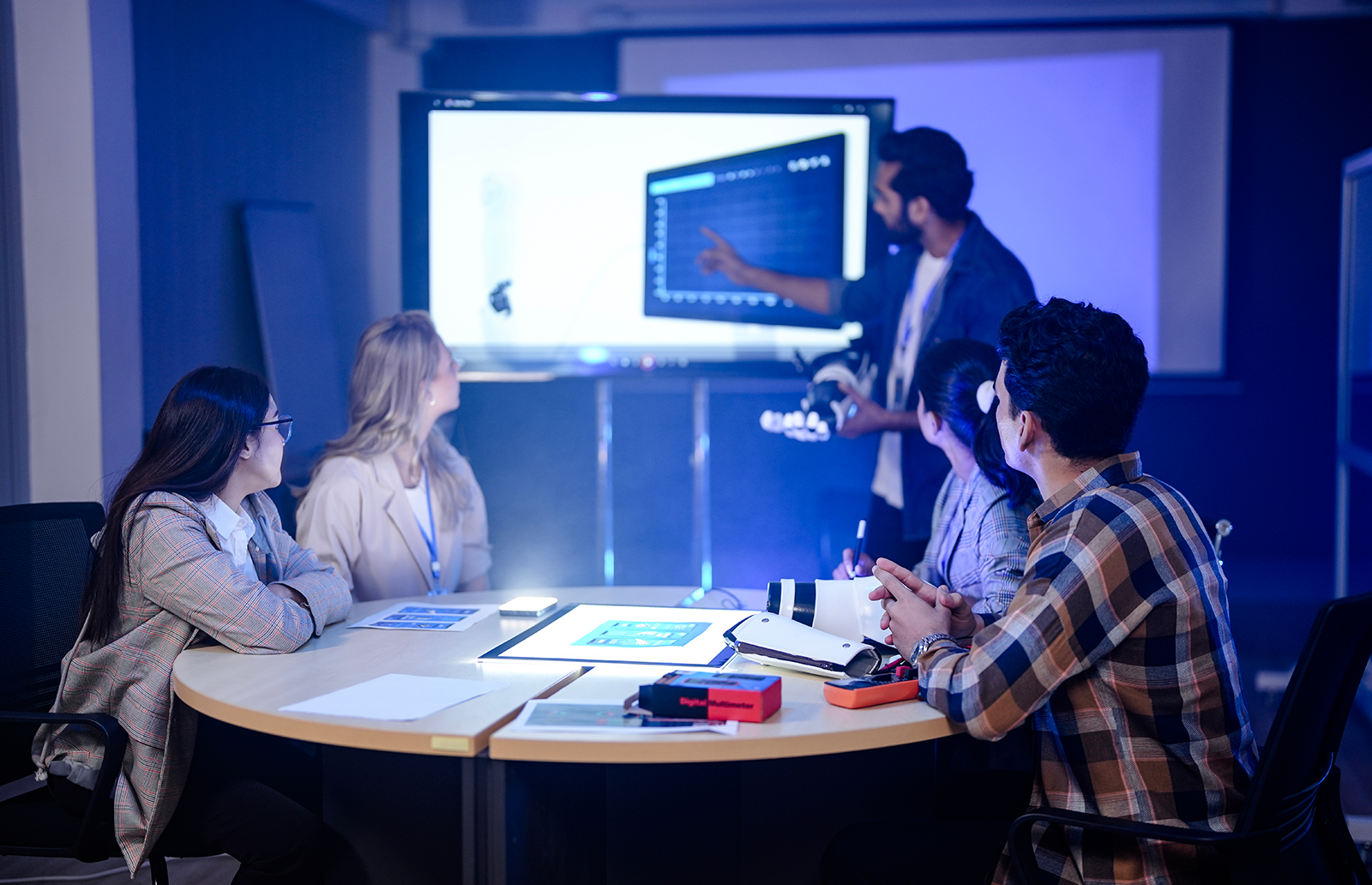 Group of men and women meeting about a robotic arm