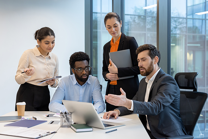 Group of professional men and women meeting in front of a laptop