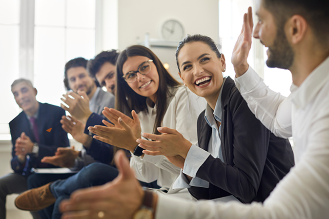 Professionals sitting and clapping for a colleague