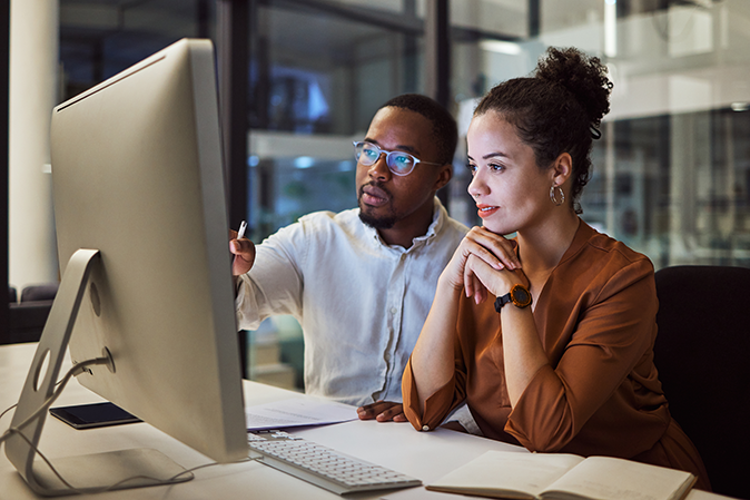 Man showing a woman something on the computer in an office