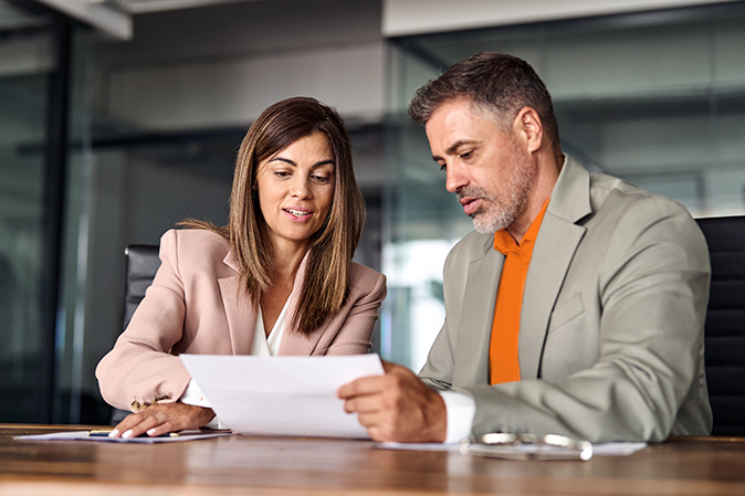 Professional man and woman going over documents sitting at a desk in an office