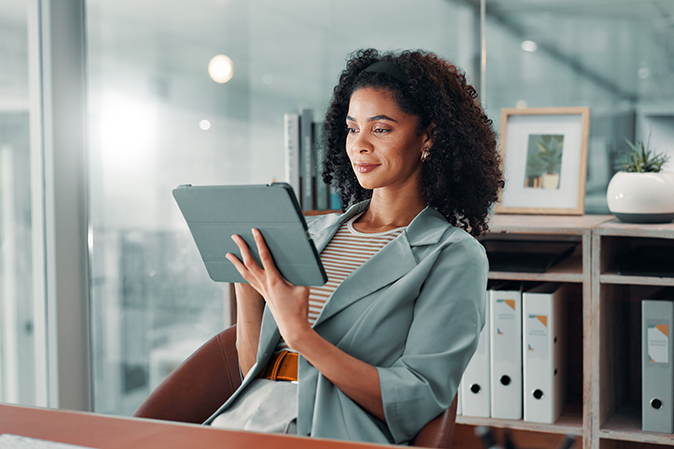 Professional woman sitting in an office working on a tablet
