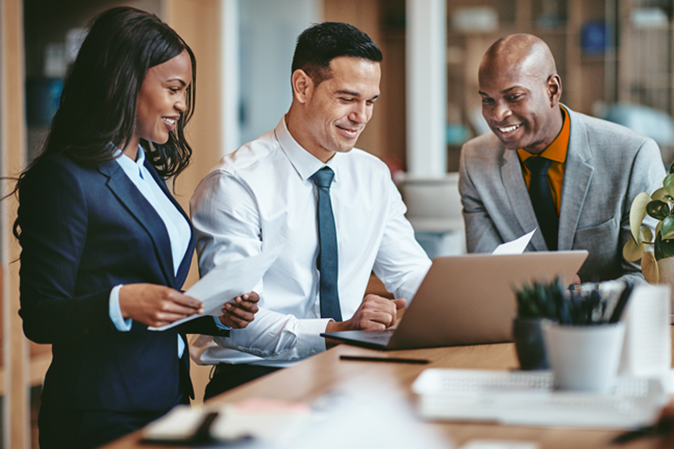 Three law firm employees gathered around a laptop and smiling