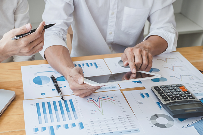 Two business people sitting at table reviewing reports