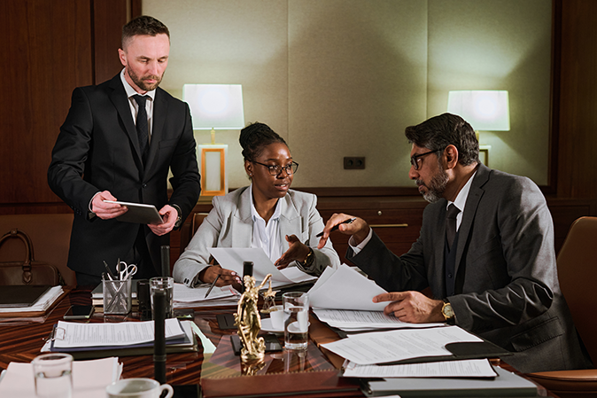 Three lawyers in an office discussing various documents