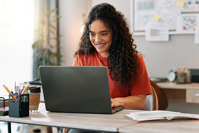Young woman working from home smiling at laptop
