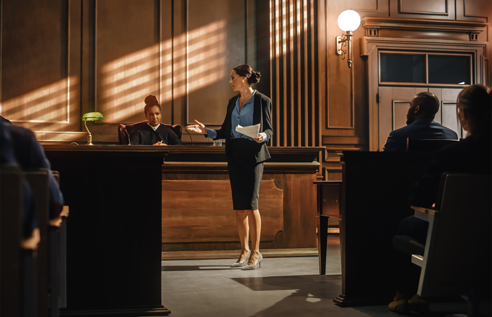 Young woman lawyer standing in front of a judget in a courtroom presenting on a case